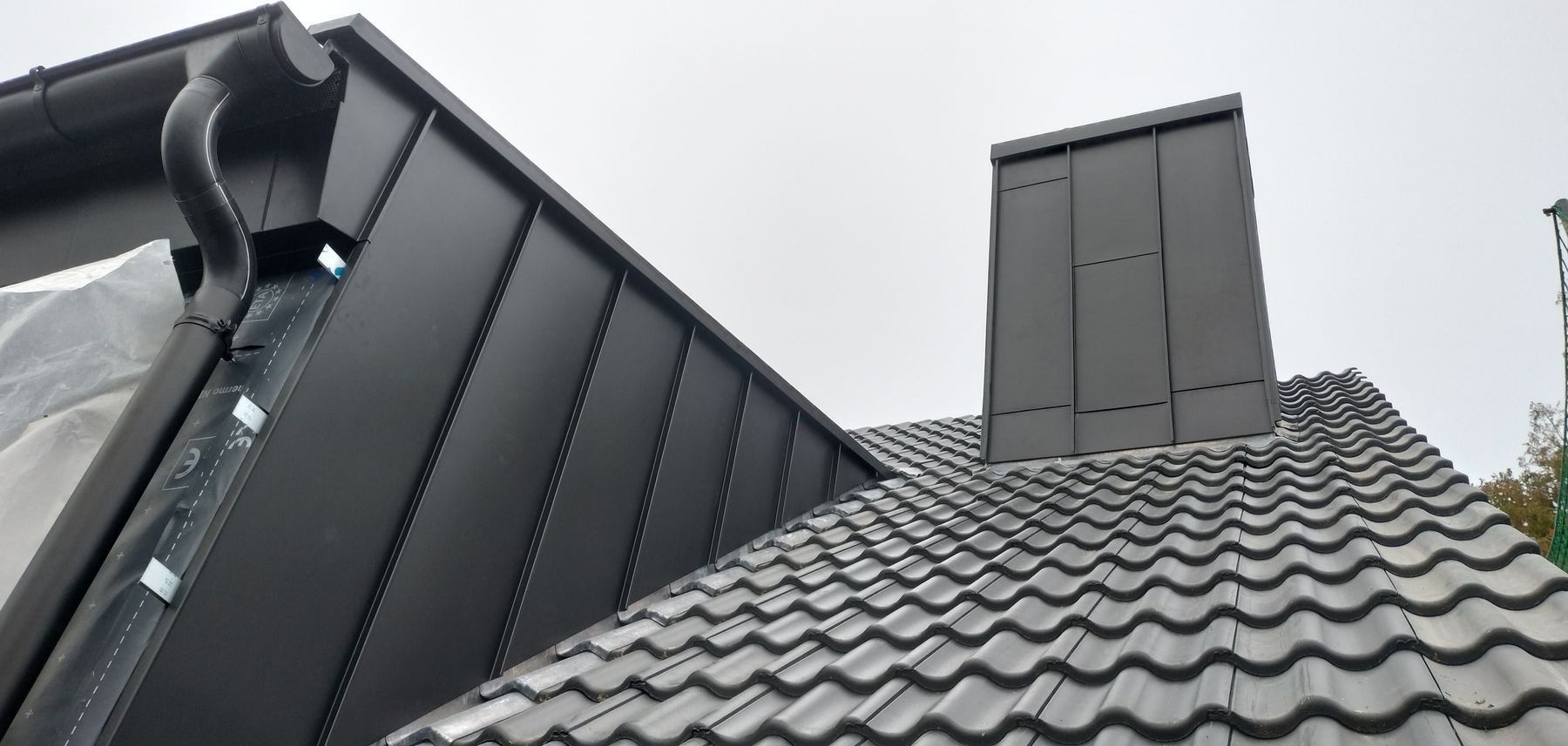 Blechverkleidung an Gaube und Kamin auf einem Ziegeldach